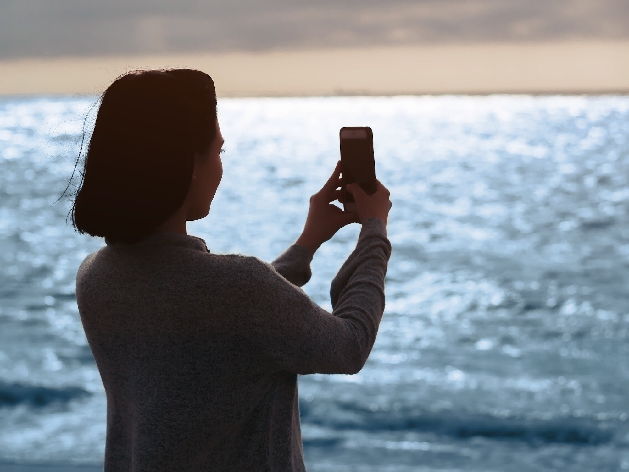 Silhouette of woman taking photo with smartphone